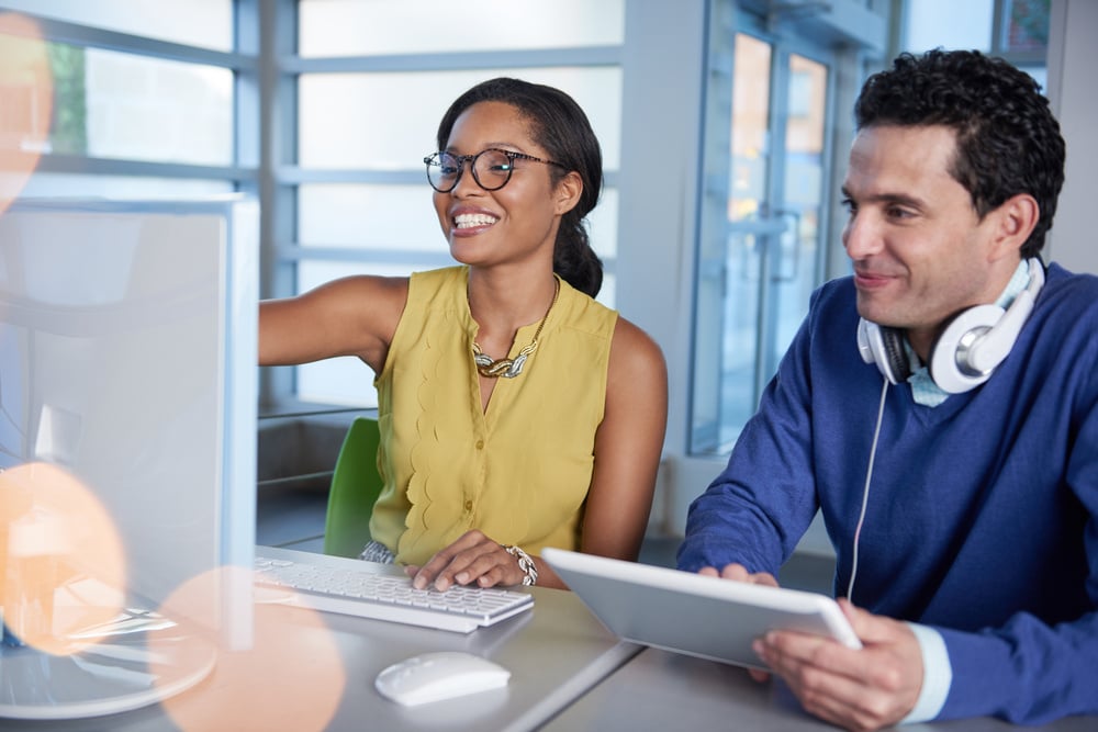 Two colleages discussing ideas using a tablet and computer-4